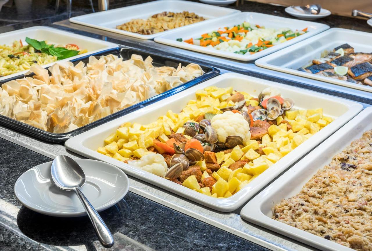 Ap Lago Montargil - Conference & Spa Exterior foto The photo shows a buffet-style display of various dishes. There are several rectangular trays filled with different types of food. 

1. One tray contains a mix of vegetables and seafood, likely including potatoes and cauliflower.
2. Another tray hold